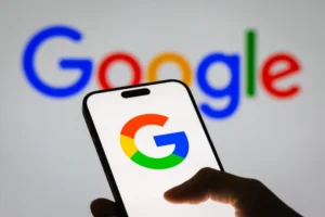 A hand holding a smartphone displaying the Google logo, with the Google wordmark in the background, representing the 2026 Google Core Update.