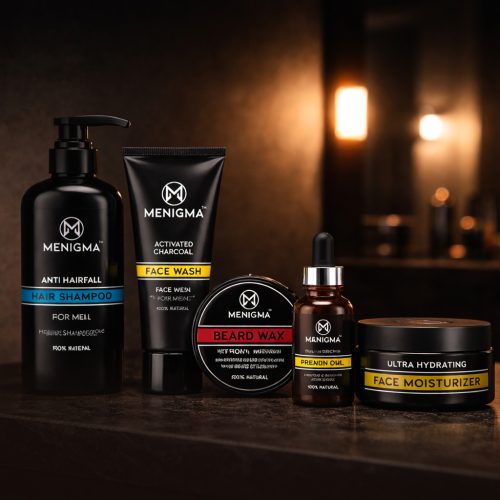 A professional product lineup of "MENIGMA" grooming supplies, including hair shampoo, activated charcoal face wash, beard wax, beard oil, and face moisturizer on a dark stone surface.